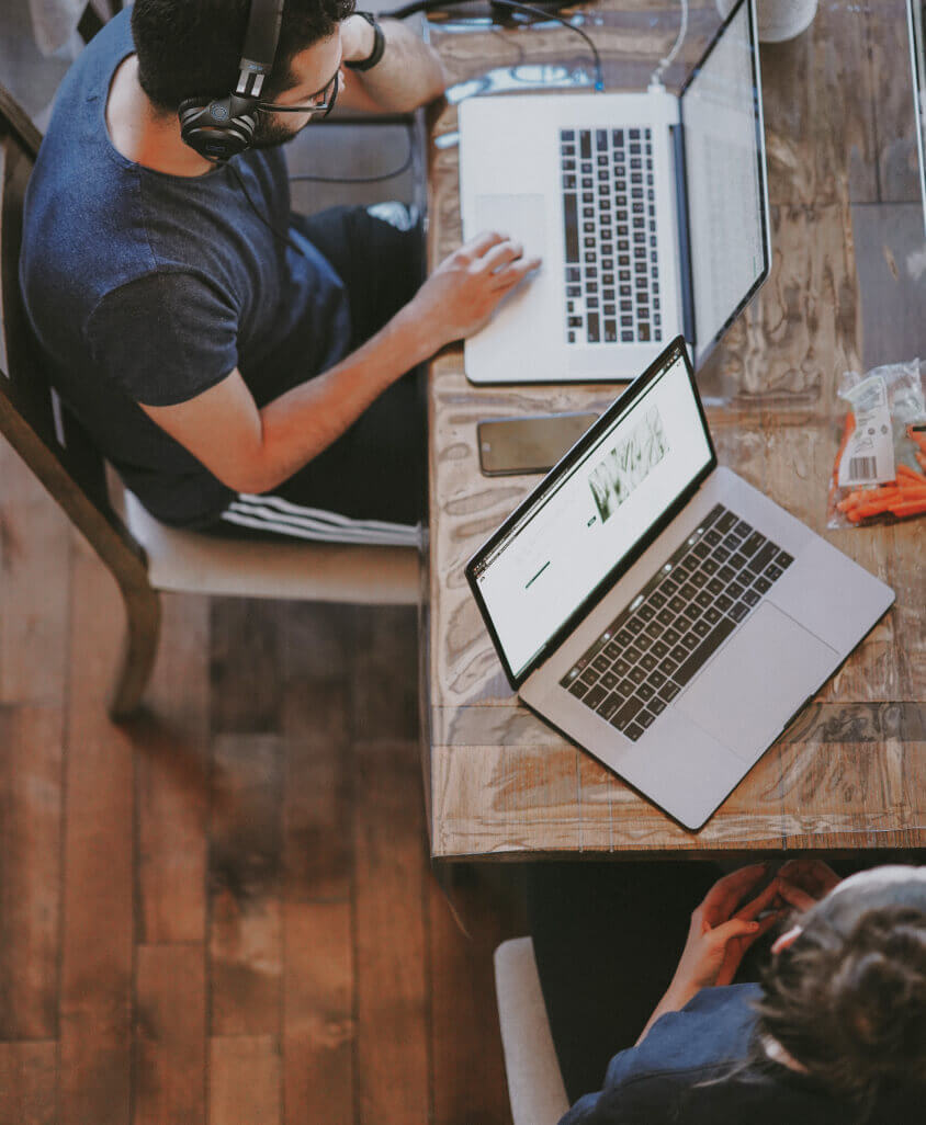 Overhead image of two people using laptops and listening to music